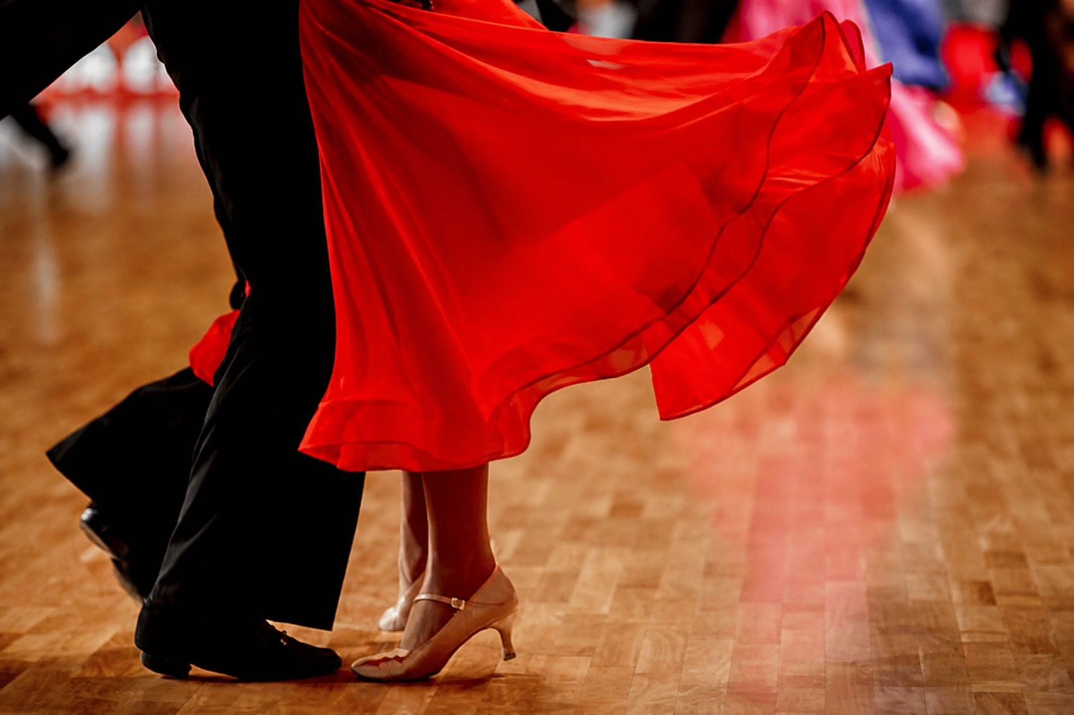 Danseurs de salon, robe rouge en mouvement sur le parquet